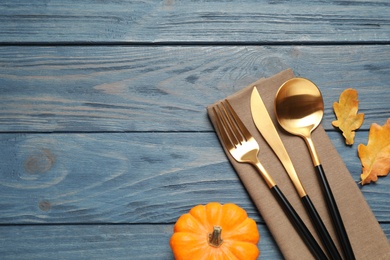 Cutlery, autumn leaves and pumpkin on blue wooden table, flat lay with space for text. Thanksgiving Day
