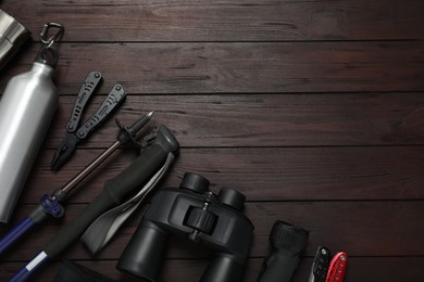 Flat lay composition with trekking poles and other hiking equipment on wooden background, space for text