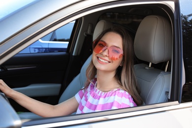 Happy woman with heart shaped glasses in car