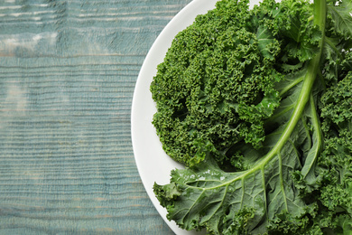 Fresh kale leaves on light blue wooden table, top view. Space for text