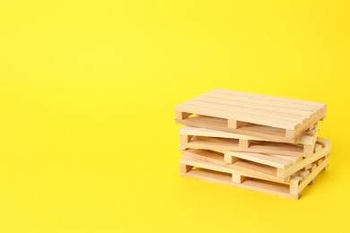 Stack of wooden pallets on yellow background, space for text