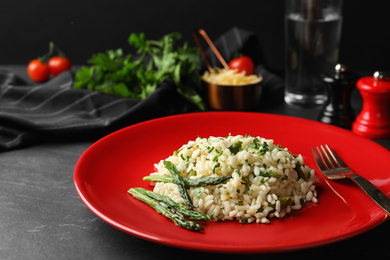 Photo of Delicious risotto with asparagus served on grey table