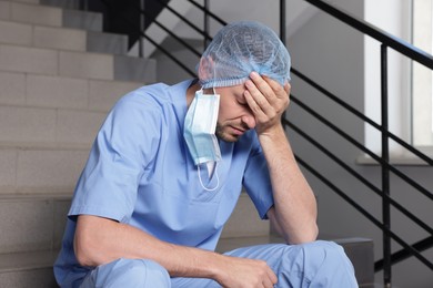 Photo of Exhausted doctor sitting on stairs in hospital