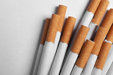 Pile of cigarettes with orange filters on white background, flat lay