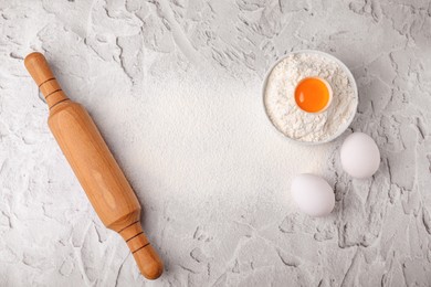 Flour, rolling pin and eggs on white textured table, flat lay