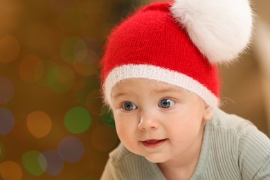Cute little baby and blurred Christmas lights on background, space for text. Winter holiday