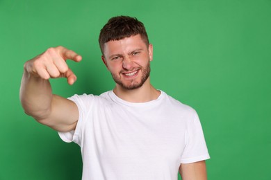 Aggressive young man pointing on green background