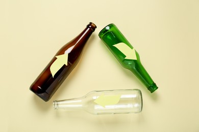 Recycling symbol made of empty glass bottles on beige background, flat lay