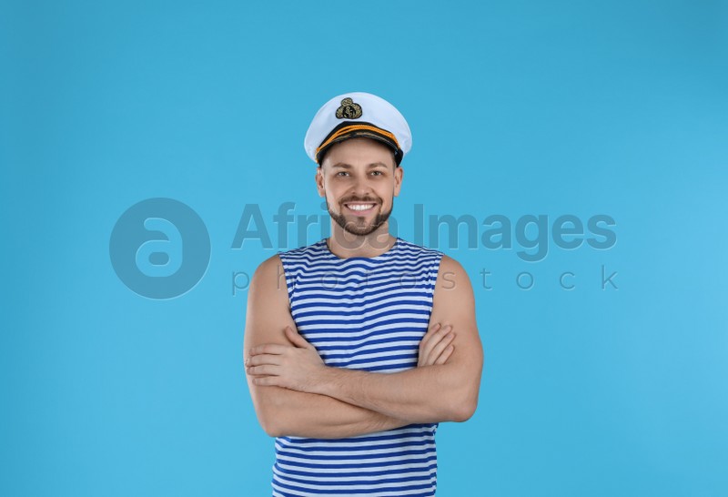 Happy sailor wearing cap on light blue background