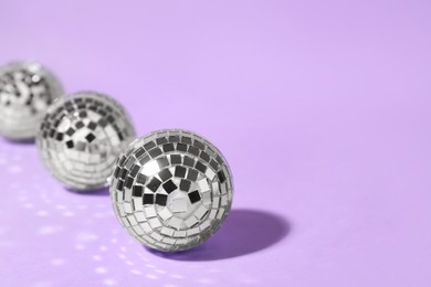 Shiny disco balls on lilac background. Space for text