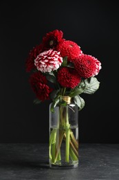 Photo of Beautiful dahlia flowers in vase on table against black background