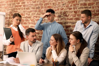 Team of employees working together on difficult task in office