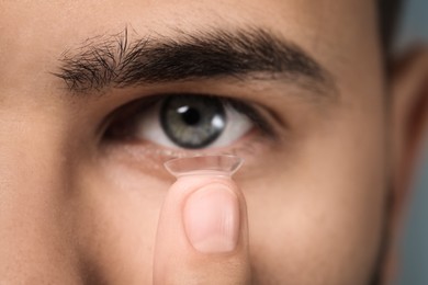 Closeup view of young man putting in contact lens