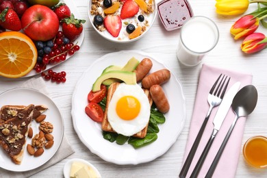 Delicious breakfast with fried egg served on white wooden table, flat lay