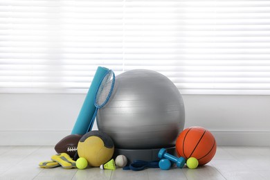 Set of different sports equipment on white floor indoors