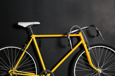 Yellow bicycle hanging on black wall, closeup
