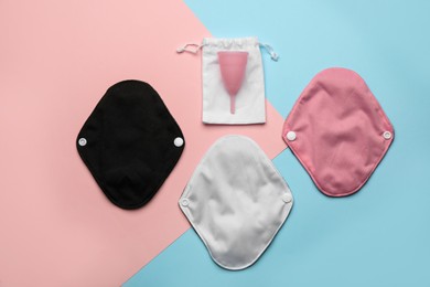 Reusable cloth pads and menstrual cup on color background, flat lay