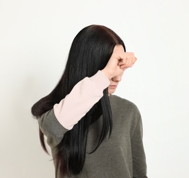 Young woman covering face against white background. Space for text