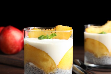 Tasty peach dessert with yogurt and chia seeds served on wooden table, closeup