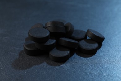 Pile of activated charcoal pills on table, closeup. Potent sorbent