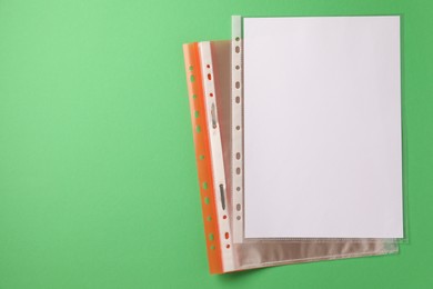 Photo of File folder with punched pockets on green background, top view. Space for text