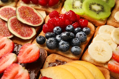 Photo of Tasty toasts with different spreads and fruits as background, closeup