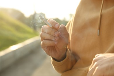 Man with cigarette outdoors, closeup of hand