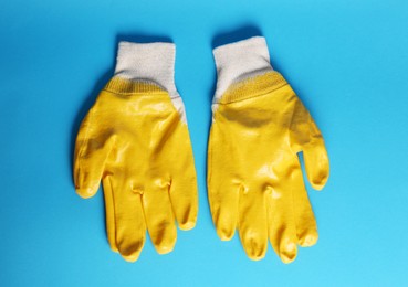 Gardening gloves on light blue background, top view