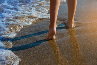 Child walking through water on seashore, closeup of legs