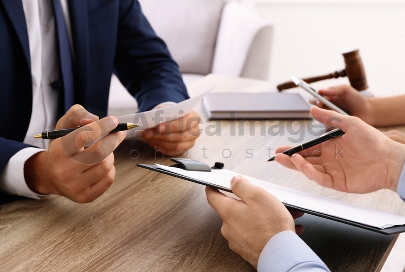 Lawyer working with clients at table in office, focus on hands