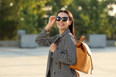 Photo of Beautiful young woman with stylish backpack on city street