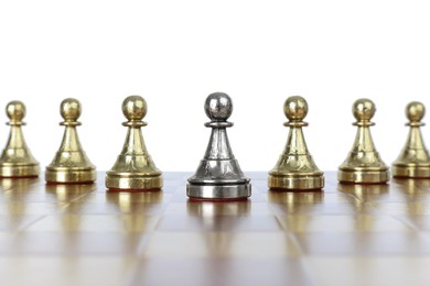 Silver pawn among golden ones on wooden chess board against white background