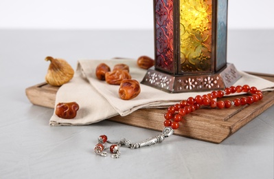 Muslim lamp, dates and prayer beads on table against white background