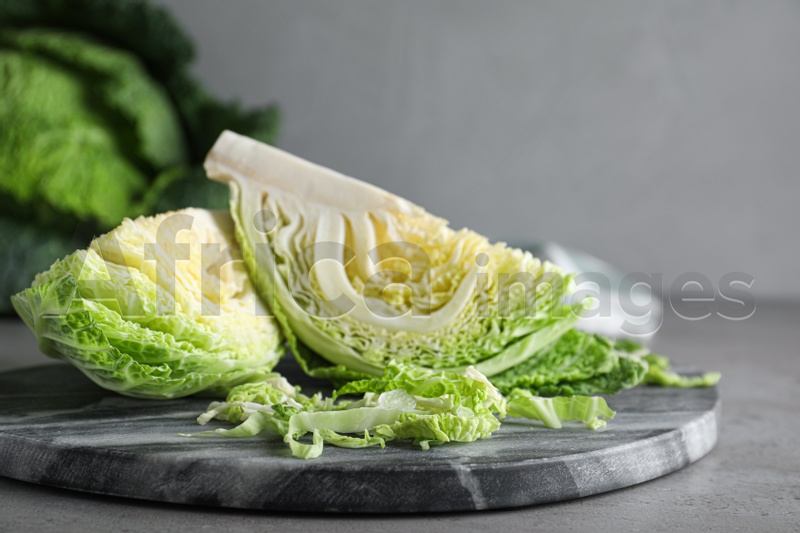 Photo of Cut fresh savoy cabbage on grey table, closeup