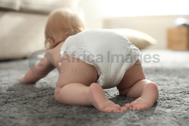 Photo of Cute little baby in diaper at home, focus on legs