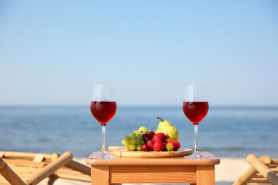Photo of Glasses with wine and fruits on table at resort