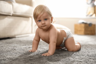 Cute little baby in diaper on carpet at home