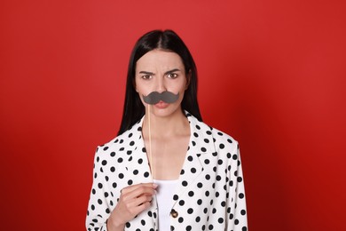 Photo of Emotional woman with fake mustache on red background