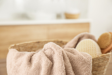 Wicker basket with clean towel in bathroom, closeup