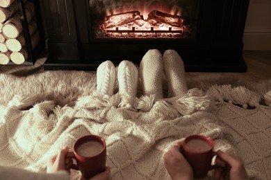 Couple in knitted socks near fireplace at home, closeup