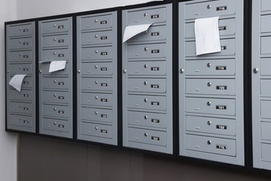 Closed grey metal mailboxes with receipts indoors