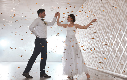 Happy newlywed couple dancing together in festive hall