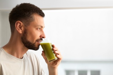 Photo of Man drinking delicious juice indoors, space for text