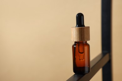Photo of Glass bottle of essential oil on dark beige background, closeup. Space for text
