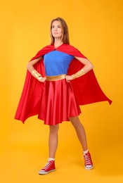 Confident woman wearing superhero costume on yellow background