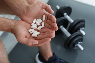 Man with handful of pills indoors, closeup. Doping concept