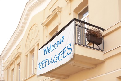 Banner with phrase WELCOME REFUGEES on building outdoors