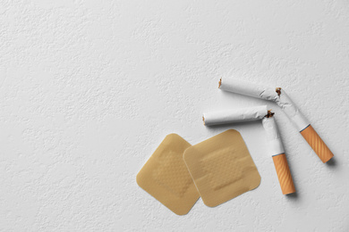 Nicotine patches and broken cigarettes on white background, flat lay. Space for text