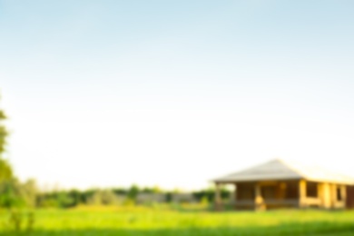 Photo of Blurred view of landscape with meadow and building on sunny day
