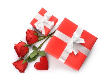 Beautiful gift boxes, roses and red heart on white background, top view. Valentine's day celebration